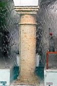 Blurred view of stone column in courtyard through glass wall