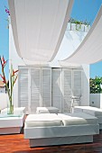 Elegant outdoor furniture with white leather upholstery under white awnings on roof terrace