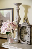 Antique table clock, candlestick, hydrangea flower and scented candle on shelf