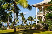 Mehrstöckiges Hotel in elegantem Kolonialstil mit umlaufender Veranda in Palmengarten