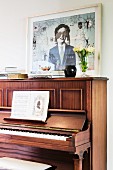 Sheet music on open piano and picture leaning on wall
