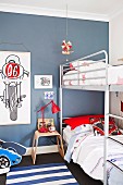 Stockbett mit Metallgestell in blau getöntem Jugendzimmer und Zeichnungen mit Motorradmotiven