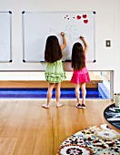 Two girls drawing on magnetic whiteboard