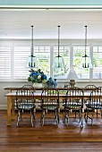 Windsor chairs at long rustic dining table in sunny dining room