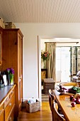 Dining room with wooden table opposite dresser and view into living room through wide, open doorway