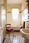 View through open door of antique wooden chair and patterned tiled floor in vintage bathroom