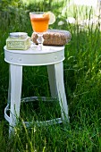 Refreshing drink and toiletries on white stool amongst green grass