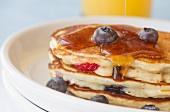Maple Syrup Pouring Over a Stack of Blueberry Strawberry Buttermilk Pancakes