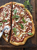 Mozzarella, Basil and Tomato Sauce Pizza with Pizza Cutter on a Cutting Board; From Above