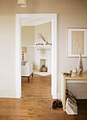 Modern desk in foyer next to open door showing continuous wooden floor and open fireplace in living room with beige colour scheme