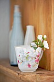 Sprig of roses in vintage cup with floral pattern