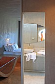 Concrete as predominant material in minimalist hotel room with ensuite bathroom; interesting arrangement of mirror images