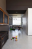 Puristischer Wohn/Essraum in umgenutztem Schulhaus; Spielzone auf poliertem Betonboden