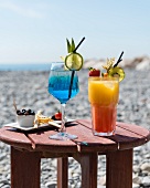 Cocktails and appetisers on a small wooden table at the beach