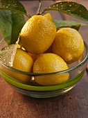 Mehrere Zitronen in Glasschale auf Holztisch