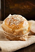 Sesame seed roll wrapped in baking parchment