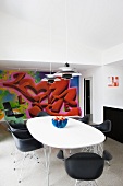 Classic, black shell chairs and table with white top in front of graffito mural on wall of modern interior