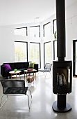 Free-standing log burner next to modern Spaghetti chair in open-plan interior with lounge area in eclectic mix of styles