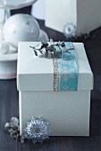 Weihnachtliche Geschenkeschachtel mit pastellfarbenem Eisblumenband und silbernen Glitzerblättern