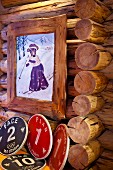 Gemaltes Bild in rustikalem Holzrahmen mit Tiermotiv in Nostalgischer Kleidung beim Skifahren an Blockhauswand