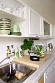 Kitchen counter with stainless steel sink; wall units with coffered doors