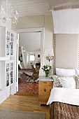 View through bedroom door into living area; bed with upholstered headboard and canopy to one side