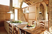 Moderner Küchenblock und Essplatz mit gedrechselten, spanischen Holzstühlen in weitläufigem, restauriertem Steinhaus