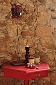 Retro table lamp on side table painted deep pink against old stone wall