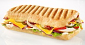 A sandwich of chicken, tomatoes, onions, gherkins, cheese slices and lettuce in a baguette