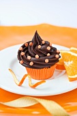 A chocolate cupcake with sugar confetti and oranges