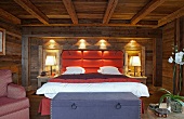Modern double bed with upholstered headboard against wall in rustic wooden cabin