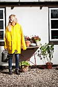 Blonde woman watering potted plants in front of house