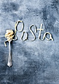 Ribbon pasta wrapped around a fork and spelling out the word pasta