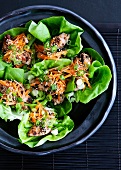 Lettuce leaves filled with chicken, carrots and sesame seeds (Asia)