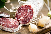 A salami, partly sliced, and cubes of parmesan