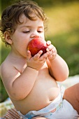 Kleines Kind beisst genussvoll in einen Pfirsich