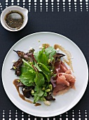 Mixed Green Salad with Prosciutto, Dry Figs, Pistachios and Balsamic Vinaigrette; On a White Plate; From Above