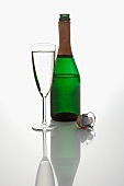 A bottle and a glass of sparking wine, and a champagne cork