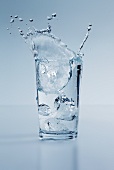 Eiswürfel fällt in ein Wasserglas