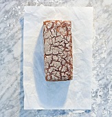 Vollkornkastenbrot auf Papier und Marmorplatte mit Mehl