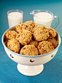 Oat biscuits in a bowl, with a jug of milk and a glass of milk