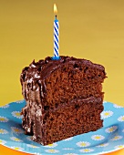 A slice of devil's food cake (chocolate layer cake, USA) with a birthday candle