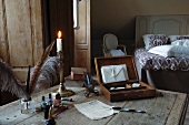 Old table in bedroom stylishly decorated with quill pens, silver candlestick and open stationary case