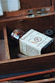 Alte Aquarellfarben-Flasche mit Etikett in französischer Sprache in einem Holzkasten
