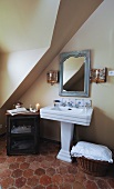 Collection of antiques around French pedestal washbasin; honeycomb patterned terracotta floor tiles