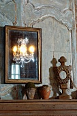 Spiegel mit Goldrahmen an Vintage Holzpaneel und Tontöpfe neben Holzskulptur auf Ablage