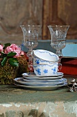 Stack of blue and white painted teacups and saucers in front of etched crystal glasses