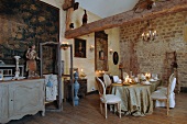 Rococo romantic atmosphere within old walls - long candlelit table festively set and surrounded by antique flea-market finds