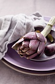 An artichoke on a purple plate