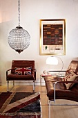 Vintage leather armchair and couch, both with stainless steel frames, and spherical glass light fitting in living room